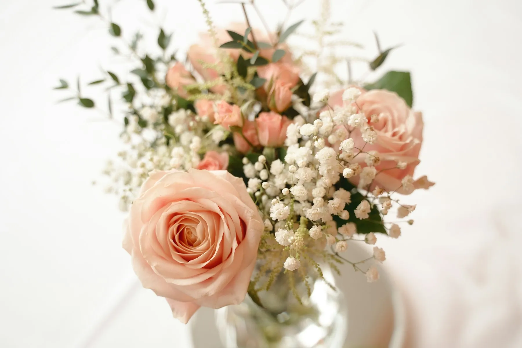 Strauß aus pfirsichfarbenen Rosen und Schleierkraut in einer Vase